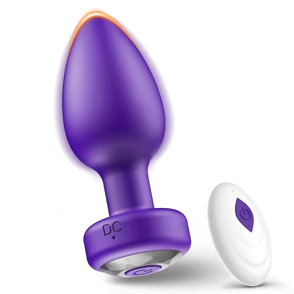 Purple vibrating butt plug with a gem base alongside a white wireless remote control.