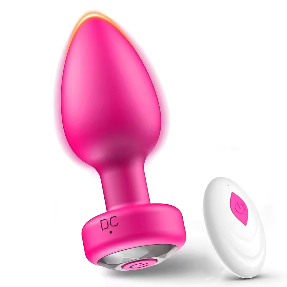 Pink vibrating butt plug with a gem base alongside a white wireless remote control.
